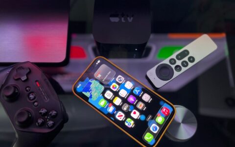 Stylish home entertainment setup featuring an iPhone, Apple TV, and gaming controller on a dark surface.