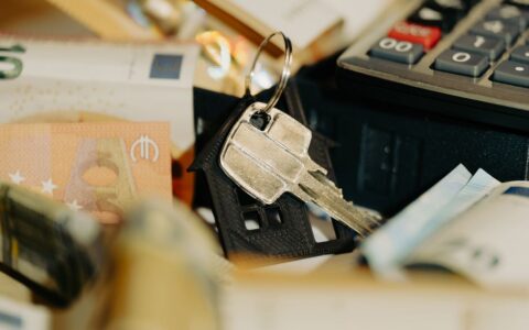 House keys rest on a keychain with euro banknotes and calculator, symbolizing real estate investment.