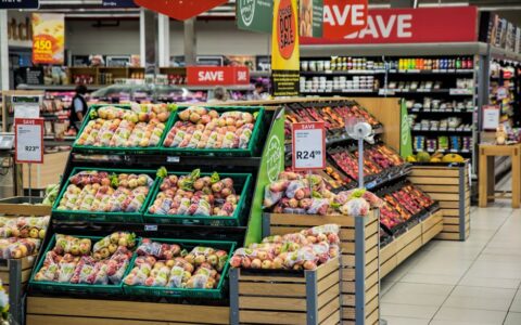 Colorful produce aisle in a supermarket showcasing fresh apples with discount signage.