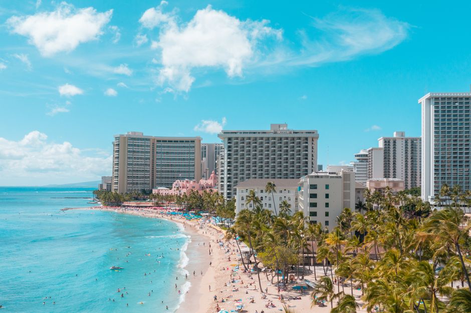 A vibrant aerial view of Waikiki Beach with luxurious hotels and sunlit turquoise ocean.