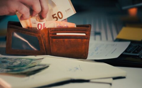 A wallet with euro banknotes and documents on an office desk, symbolizing finance and budgeting.