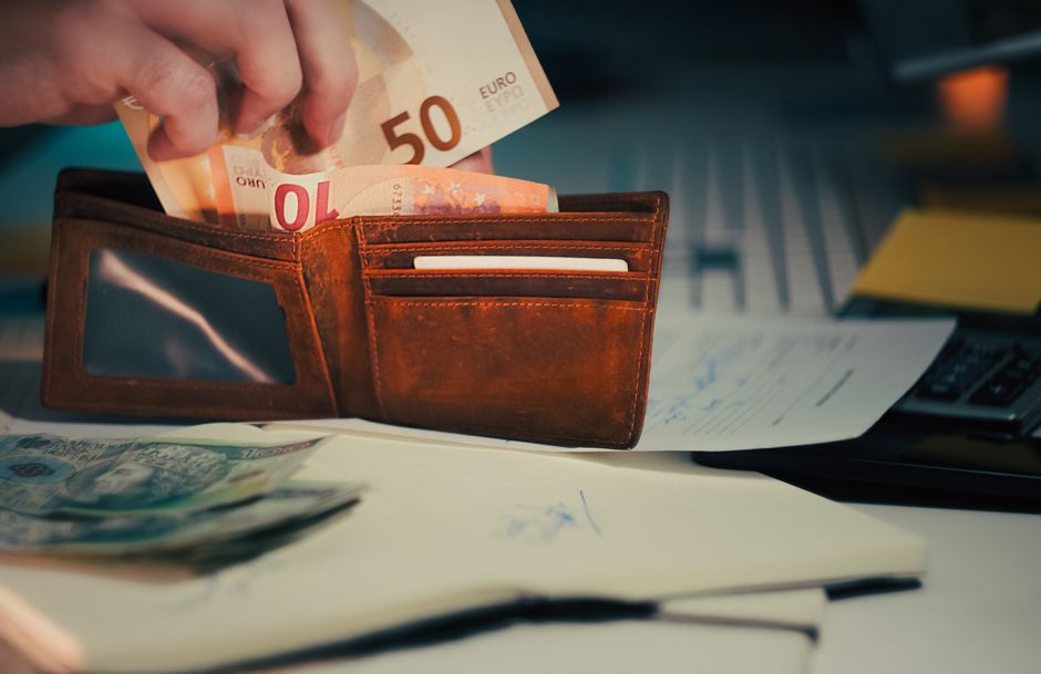 A wallet with euro banknotes and documents on an office desk, symbolizing finance and budgeting.