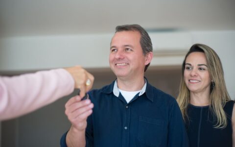 Smiling couple receiving keys, celebrating new home purchase indoors.