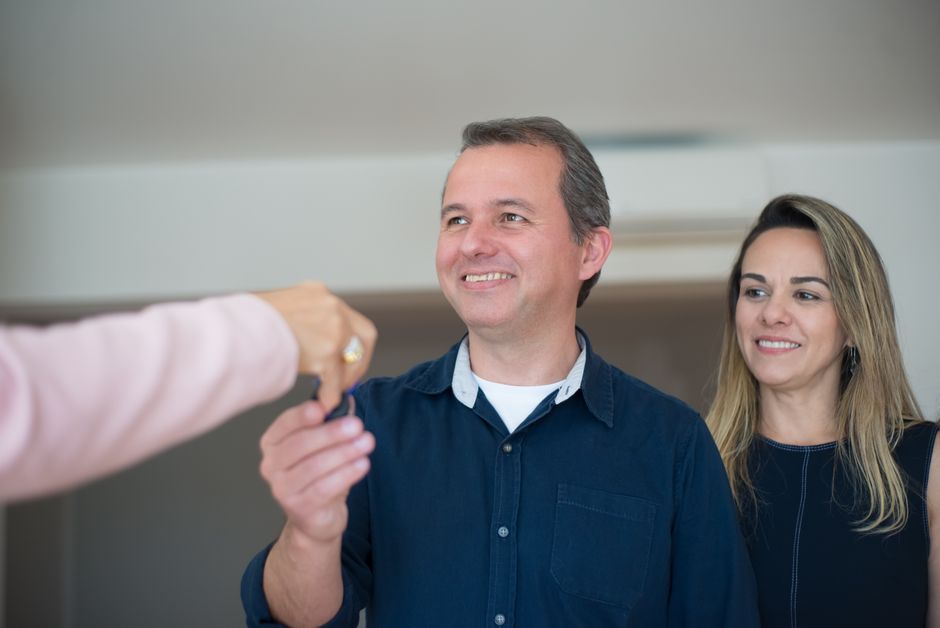 Smiling couple receiving keys, celebrating new home purchase indoors.