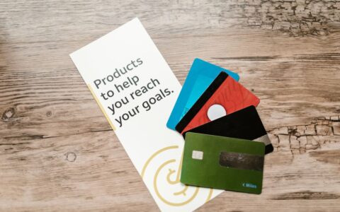 Assorted credit cards on a wooden table next to a leaflet with motivational text about financial goals.