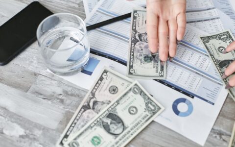 A top view of financial documents with dollar bills and a glass of water, emphasizing budgeting.