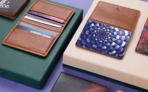 Close-up of assorted leather wallets and cardholders on a modern violet and green background.
